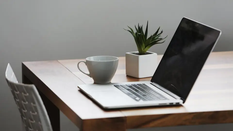 Ein Dating-Profil in Ruhe schreiben: Laptop und Tasse auf einem Tisch am Fenster