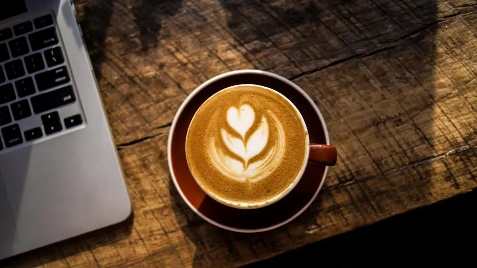 Erstes Date im Café: ein Cappuccino mit Milchschaum auf einem Holztisch