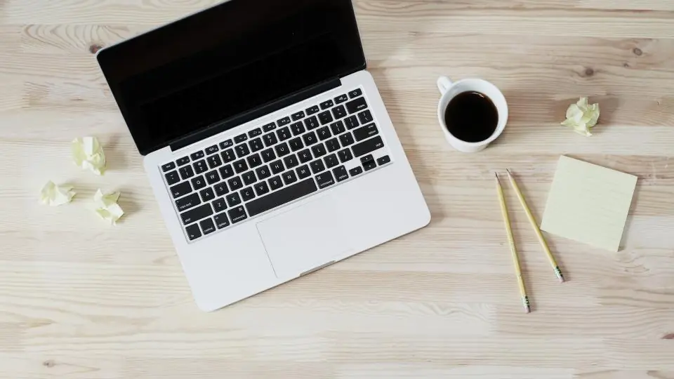 So funktionieren Dating Seiten: ein aufgeklappter Laptop und eine Tasse Kaffee auf einem hellen Holztisch