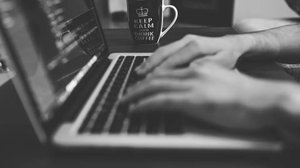 Wer Love Scam erkennen will, prüft Profile am Laptop: Hände tippen neben einer Tasse