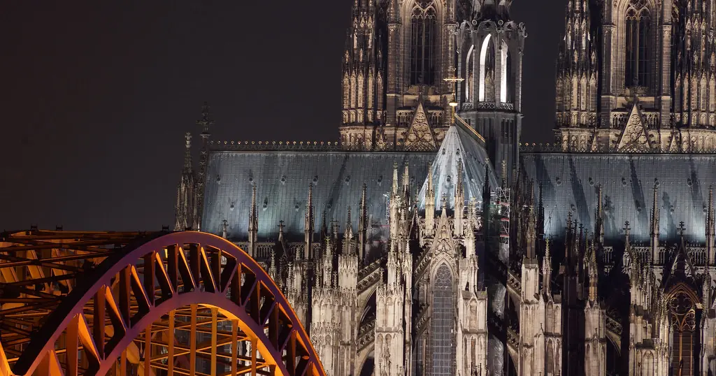 Dating Seiten Köln: der beleuchtete Dom hinter einem Bogen der Hohenzollernbrücke bei Nacht